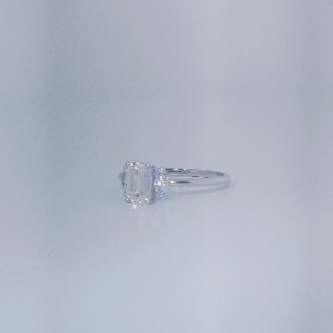 Female Wedding Ring, 14K White Gold, emerald-cut central Diamond (E/VS1, 1.02ct) flanked by 2 round Diamonds (0.25ct total).