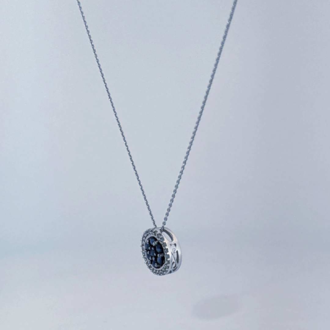 14K White Gold Necklace, set with 7 Blue Sapphires in a circular pendant surrounded by smaller clear stones.