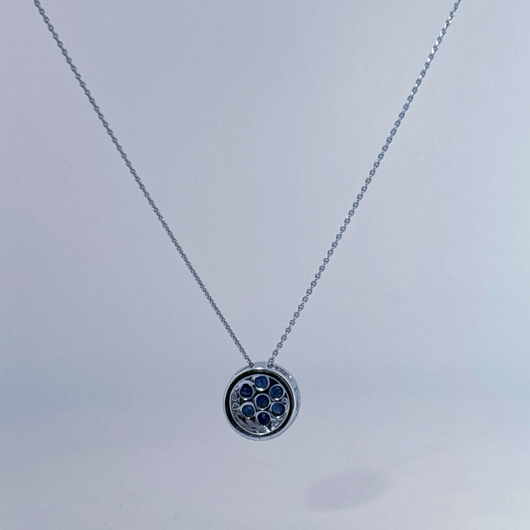 14K White Gold Necklace, set with 7 Blue Sapphires in a circular pendant surrounded by smaller clear stones.