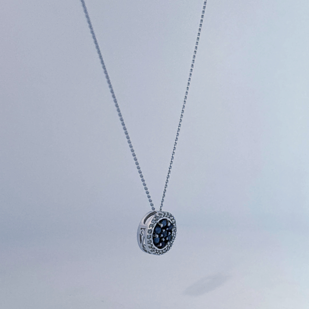 14K White Gold Necklace, set with 7 Blue Sapphires in a circular pendant surrounded by smaller clear stones.